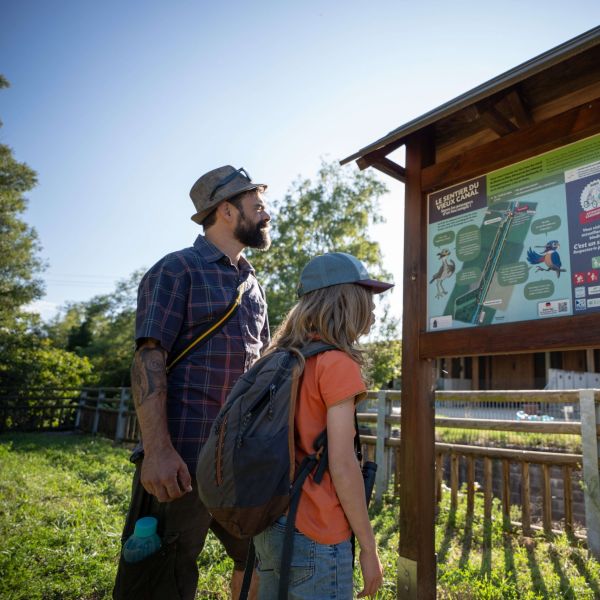 Famille lisant un panneau du sentier de la Maison de la nature à Hirtzfelden
